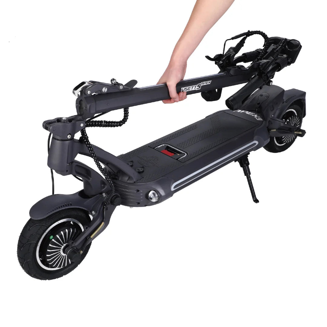 Ruka drži sklopljeni crni električni romobil Vsett 9 Apex prikazan iz poluprofila na bijeloj