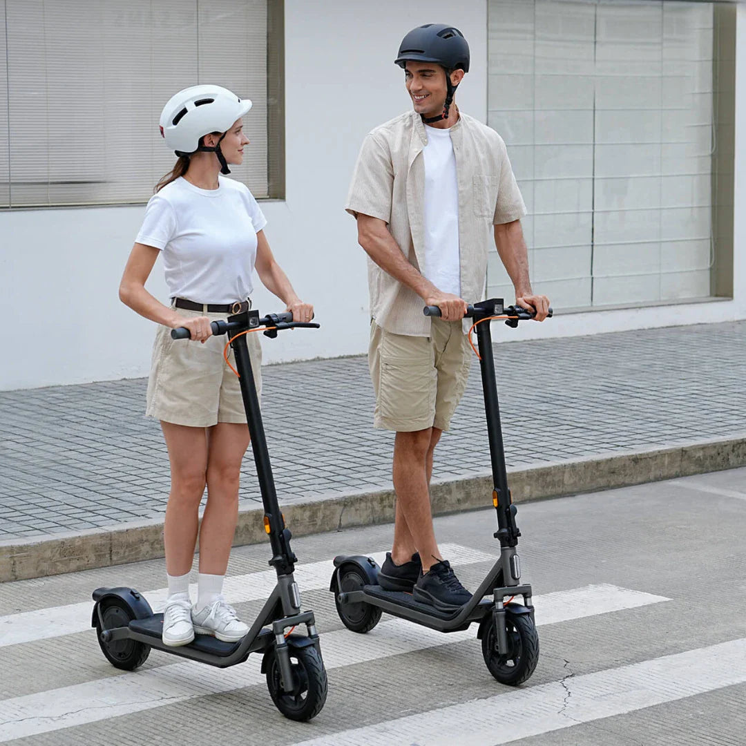 Par vozi crni električni romobil Xiaomi Mi Electric Scooter 6 Lite na pješačkom prijelazu