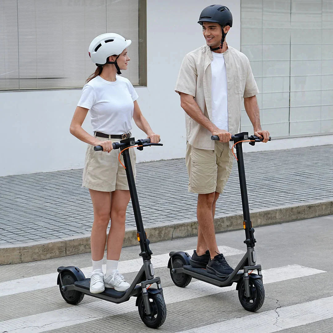 Muškarac i žena voze sivi električni romobil Xiaomi Mi 6 Lite na pješačkom prijelazu