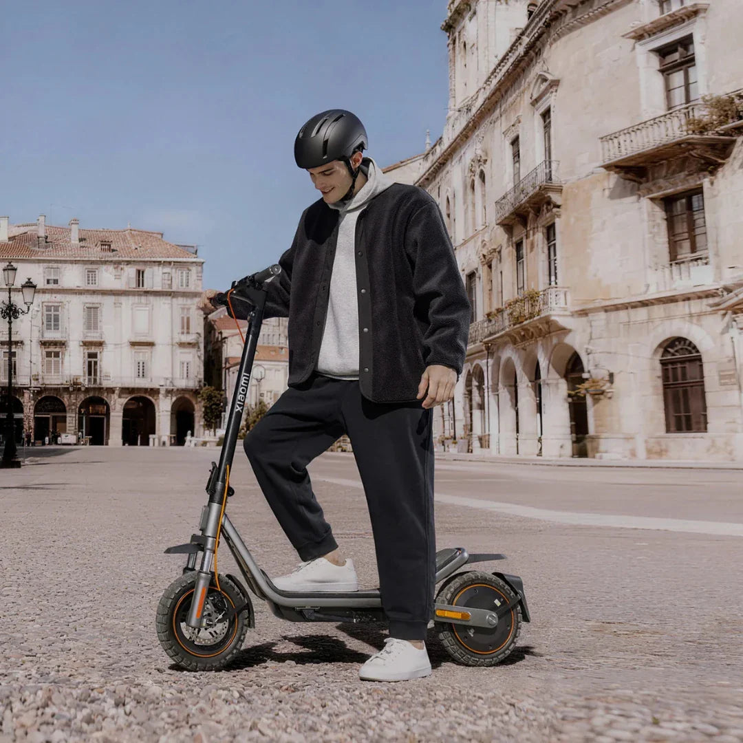 Muškarac s kacigom vozi sivi električni romobil Xiaomi 6 Pro na gradskom trgu