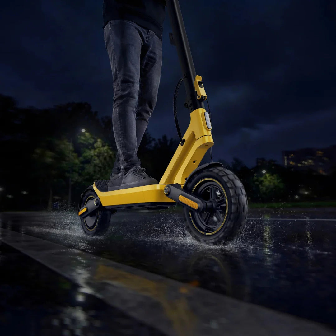 Žuti električni romobil Xiaomi 6 Ultra u vožnji po kiši po mokrom asfaltu noću