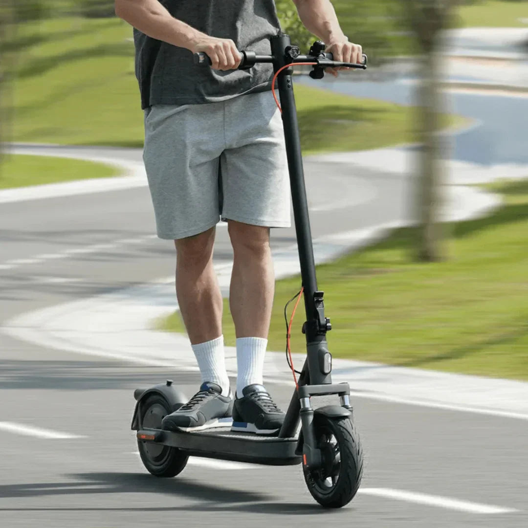 Muškarac vozi crni električni romobil Xiaomi Elite na asfaltiranoj stazi u parku