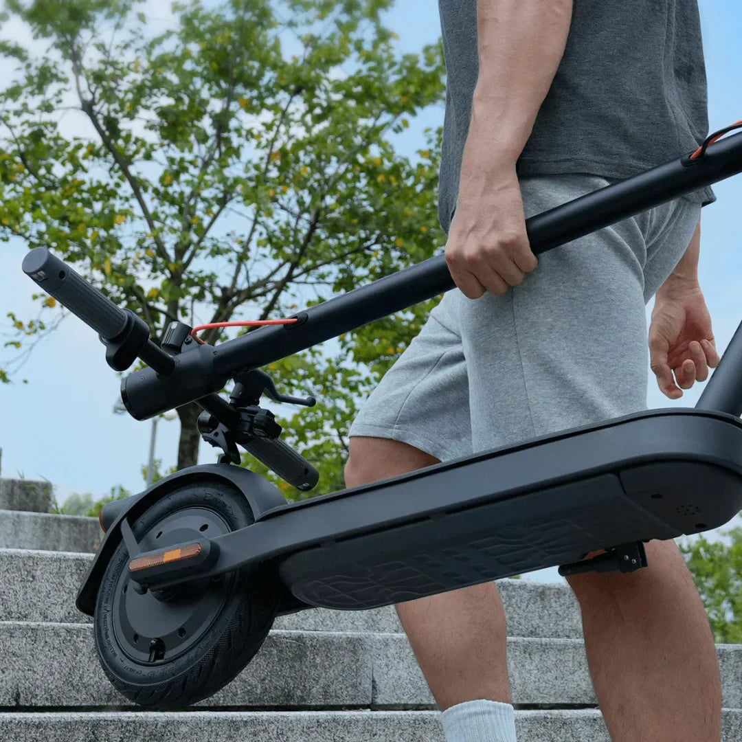 Muškarac nosi sklopljeni crni električni romobil Xiaomi Elite na stepenicama