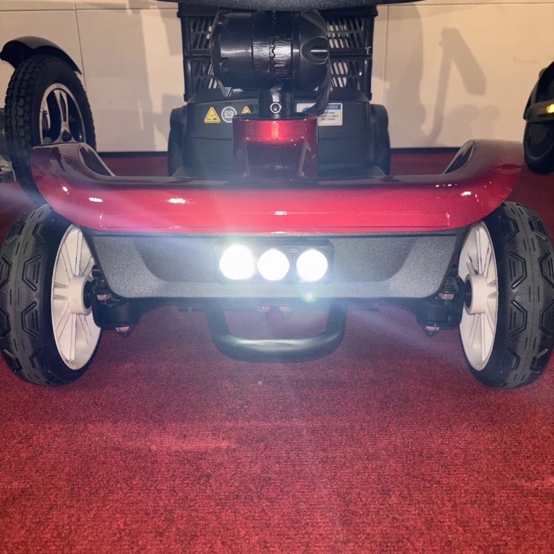 Prednji pogled na crveni električni skuter Rollvita Base s upaljenim LED svjetlima
