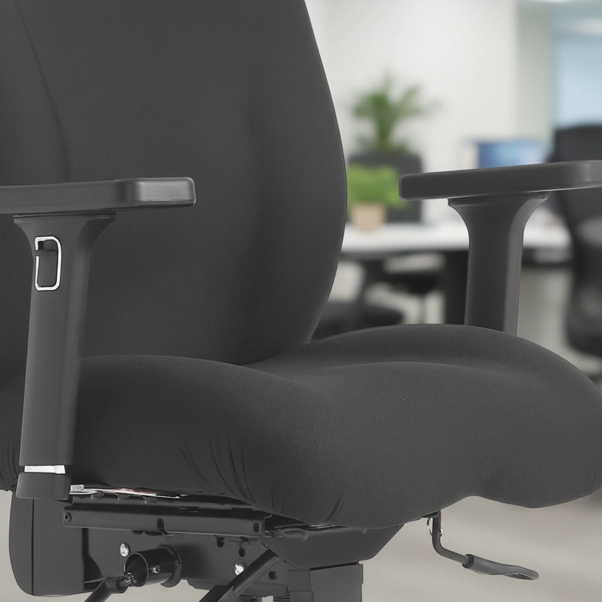 Proizvod je ergonomska uredska stolica, točnije model Hercules. Slika prikazuje krupni plan sjedala i naslona za ruke stolice, s elegantnim crnim presvlakama od tkanine i čvrstim dizajnom. Pozadina sugerira moderno uredsko okruženje, naglašavajući njegov profesionalni izgled.