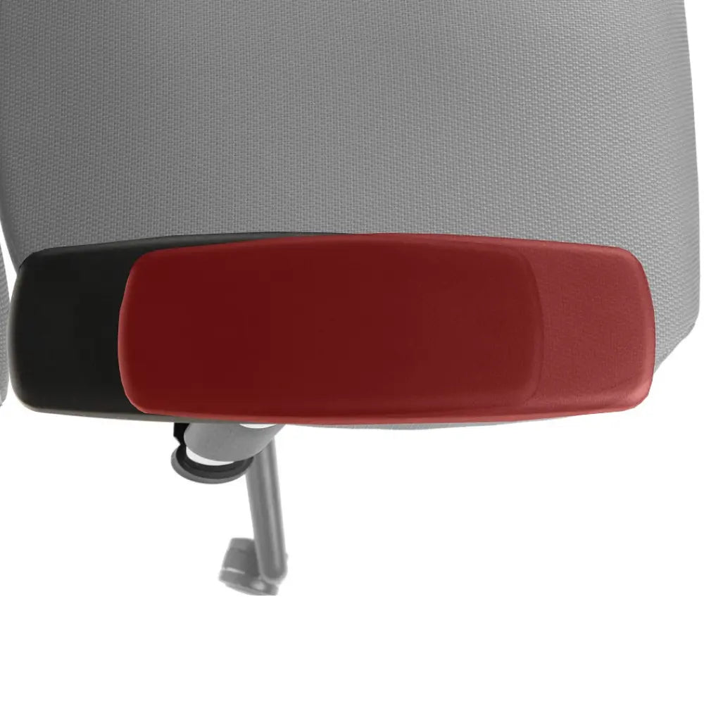 Slika prikazuje ergonomsku uredsku stolicu, točnije model Kenton. Prikazuje krupan plan naslona za ruke, koji ima crveni jastuk na crnoj bazi, ističući njegov dizajn i značajke udobnosti. Pozadina sugerira teksturiranu tkaninu, tipičnu za ergonomske stolice.