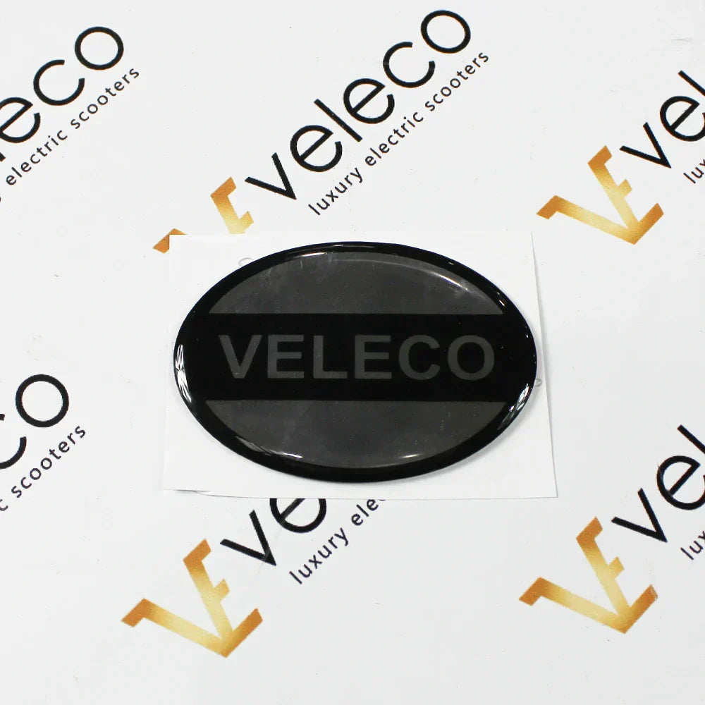 Crna ovalna naljepnica s logotipom Veleco za kutiju za zaključavanje skutera Faster