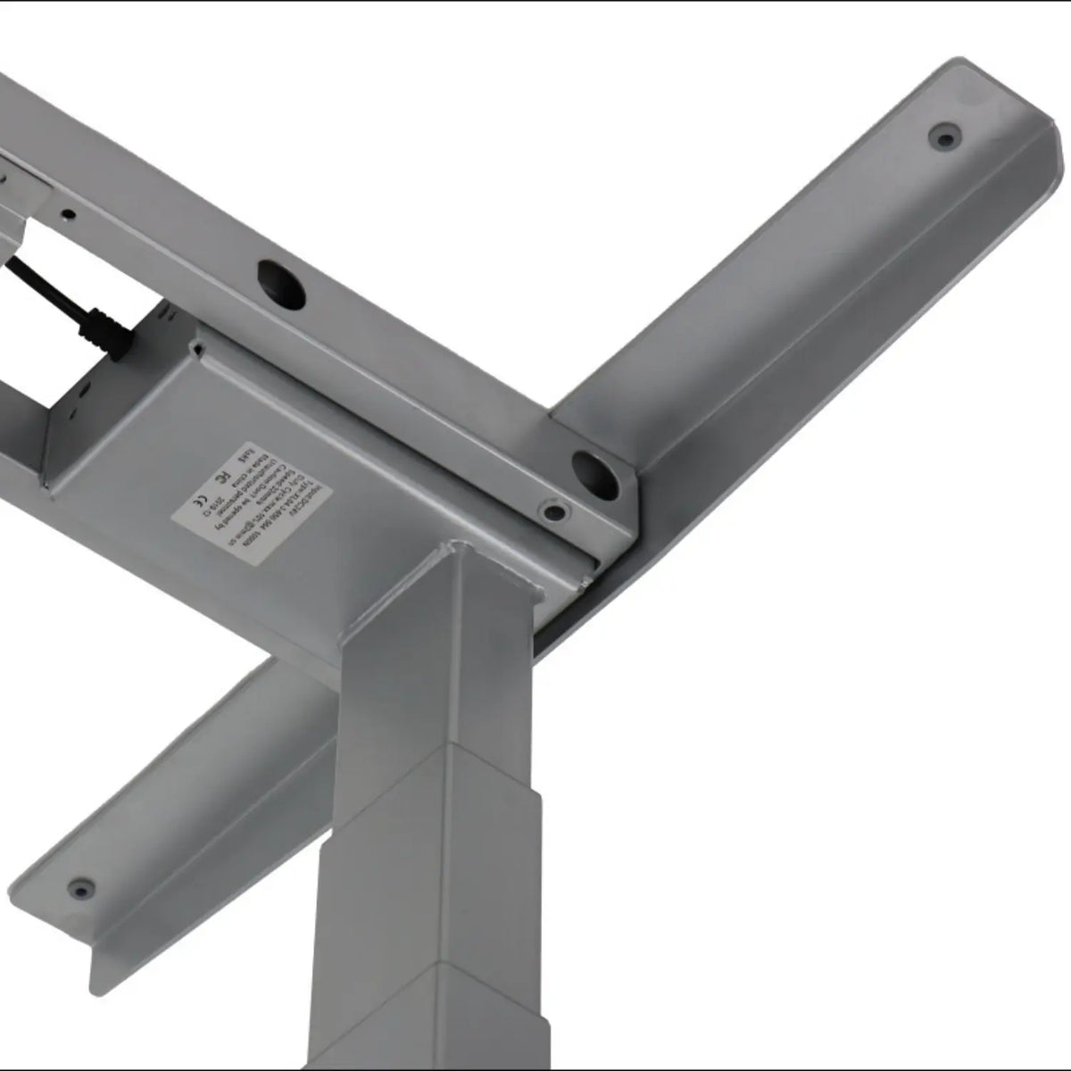 Slika prikazuje postolje podiznog stola, točnije model UT04-2T. Odlikuje se elegantnim, metalnim dizajnom s naglaskom na stabilnost i prilagodljivost. Vidljive komponente uključuju noge i poprečnu gredu okvira, zajedno s upravljačkom kutijom koja pokazuje da je dizajniran za podešavanje visine.