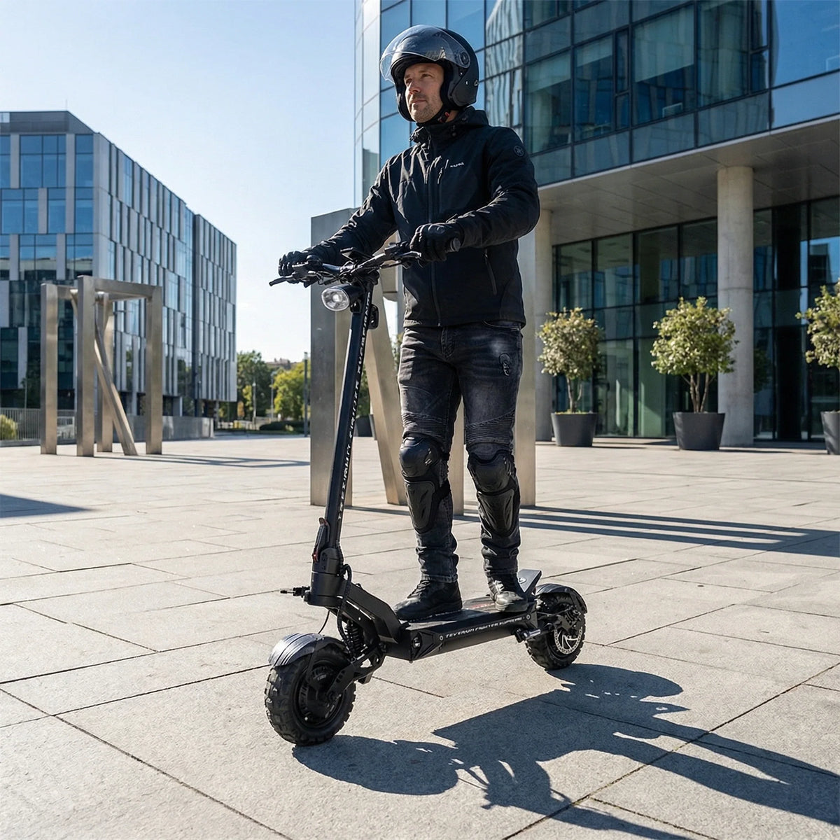 Muškarac s kacigom vozi crni električni romobil Teverun Fighter Supreme 2023 ispred moderne zgrade