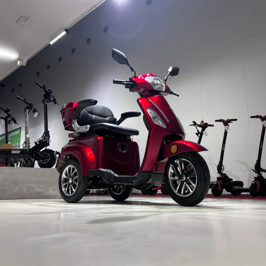 Crveni električni skuter za starije osobe Vigorous Vista 1 s tri kotača u izložbenom prostoru, bočni pogled